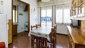 A dining area with a table, chairs, a television, and a kitchen in the background. - Accogliente # trilocale 100mt from the sea# (Jesolo)