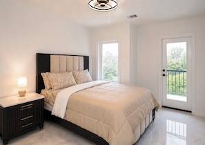 A bedroom with a bed, nightstand, lamp, and a door leading to a balcony. - FIFA World Cup ‘26! 2 Bedroom, 2.5 Bath (Houston)