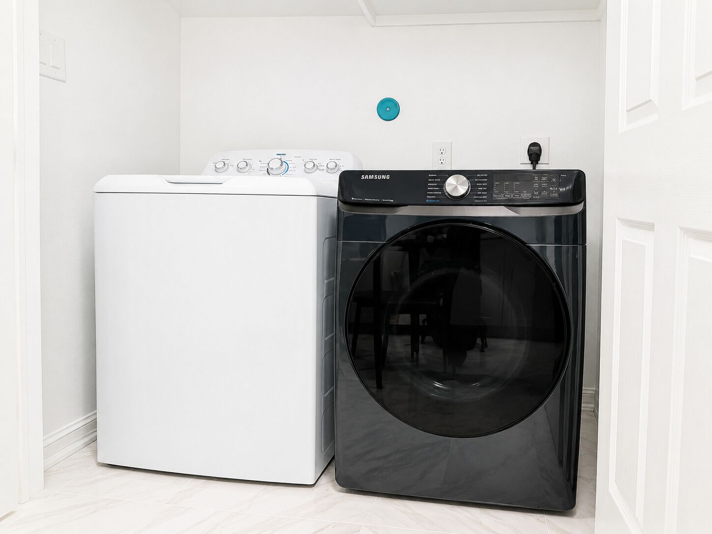 Une buanderie avec un lave-linge blanc et un sèche-linge noir.