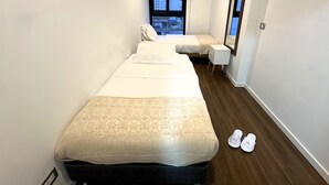 A narrow hotel room with a large bed, a smaller bed, a bedside table, a mirror, and a window with a view. - Aparts4Days 2 Bedroom Apartment 4405 (Miraflores)