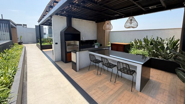An outdoor kitchen area with a grill, bar counter, and seating. - Aparts4Days 2 Bedroom Apartment 4405 (Miraflores)
