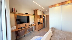 Un espacio habitable compacto con kitchenette, televisor de pantalla plana, sofá y zona de comedor.