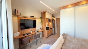 A compact living space with a kitchenette, a flat-screen TV, a sofa, and a dining area. - Stay Refuge | Your refuge minutes from the airport (Guarulhos)