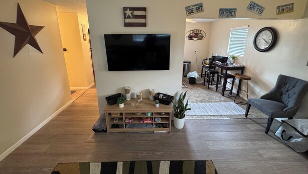 Un salon avec un téléviseur, une décoration en forme d’étoile, une horloge et, au fond, un coin repas.