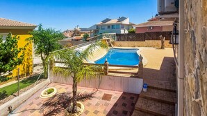Zona residencial con piscina, jardín cercado y un edificio con paneles solares.