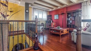 Una sala de estar con una escalera, muebles de madera, una estantería y un reloj en la pared.