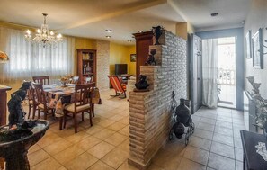 Zona pranzo con lampadario, camino e tavolo con sedie.