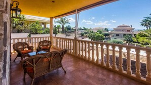 Un balcón con muebles de mimbre y vista a una zona residencial.