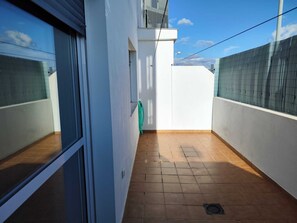 A narrow balcony with a tiled floor, white walls, and a green hose. - Nice apartment with garage in Conil. (Conil De La Frontera)