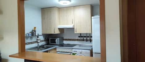 A kitchen with wooden cabinets, a microwave, an oven, and a sink.