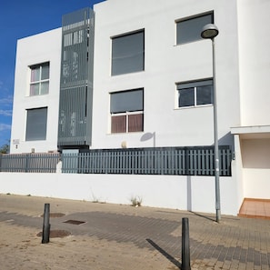 A modern building with a white facade, multiple windows, and a metal fence. - Nice apartment with garage in Conil. (Conil De La Frontera)