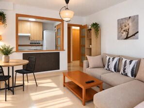 A modern living room with a sofa, coffee table, and dining area with chairs. - Nice apartment with garage in Conil. (Conil De La Frontera)