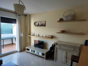 A living room with a TV, shelves, a cabinet, and a window with curtains. - Nice apartment with garage in Conil. (Conil De La Frontera)