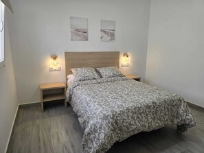 Ein Schlafzimmer mit einem Bett, Nachttischen, Wandleuchten und zwei gerahmten Bildern.