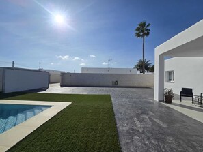 A modern outdoor area with a swimming pool, a grassy lawn, and a paved walkway. - Beautiful New House with a Private Pool (Conil De La Frontera)