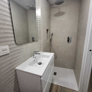 Ein modernes Badezimmer mit einem weißen Waschbecken, Spiegel und Dusche.