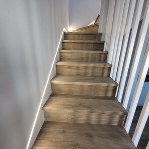 Eine Holztreppe mit weißen Geländern und einer Lichtleiste am Rand.