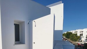 Ein Balkon mit kleinem Fenster, einer Dusche und Blick auf die Straße.