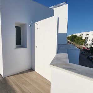 Ein Balkon mit kleinem Fenster, einer Dusche und Blick auf die Straße.