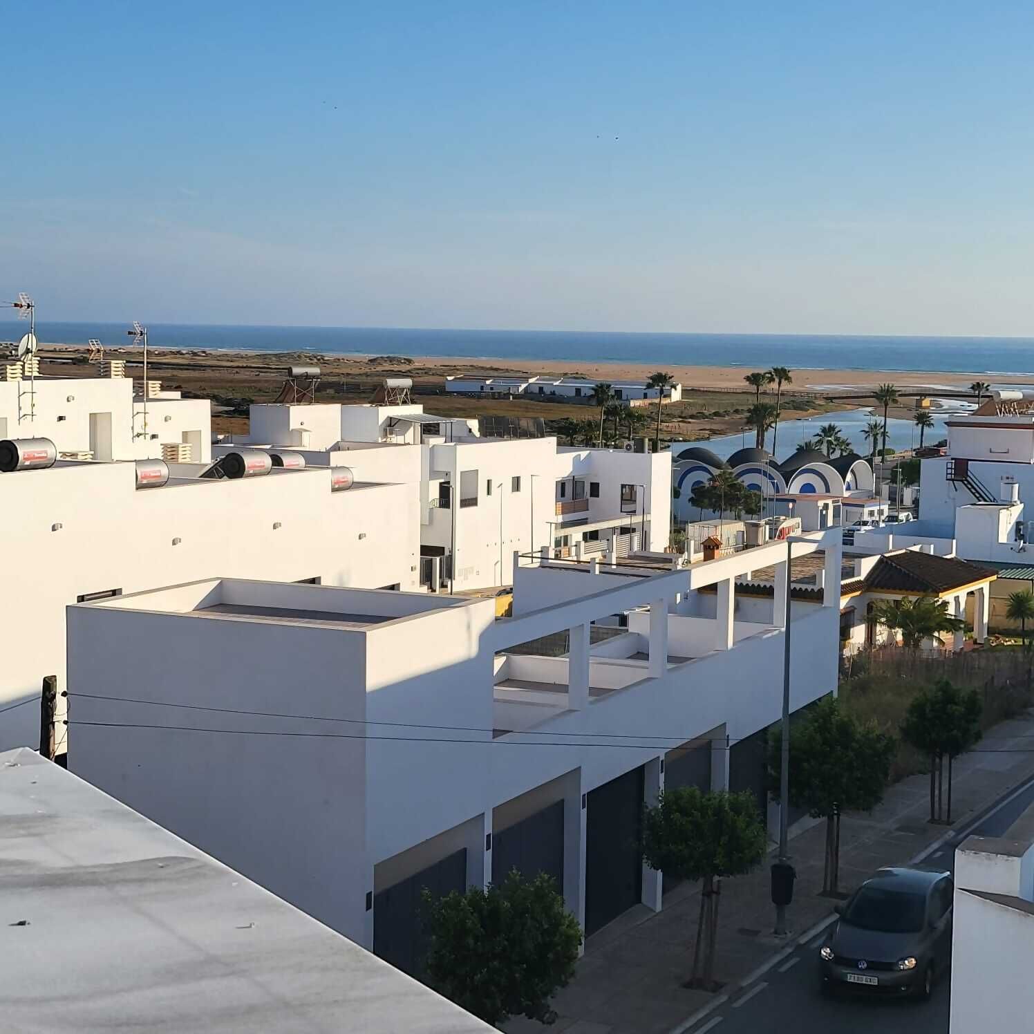 Ein Küstenwohngebiet mit weißen Gebäuden, einer Straße und Blick auf den Strand.