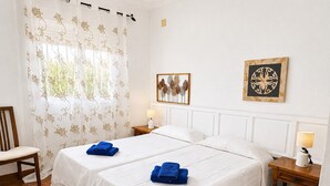 A hotel room with two beds, a chair, a window with curtains, two bedside tables with lamps, and wall art. - P1 - With pool and garden, minutes from the sea. (Conil De La Frontera)