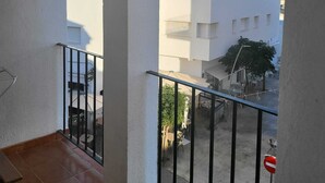 Een balkon met uitzicht op een woongebied, met witte gebouwen en een heldere lucht.