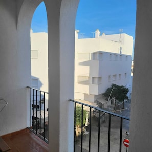 Ein Balkon mit Blick auf ein Wohngebiet, mit weißen Gebäuden und blauem Himmel.