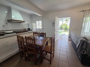 A kitchen with a dining table and chairs, a built-in oven, and a view of the outdoors. - Coquettish house with private area near the sea (Conil De La Frontera)