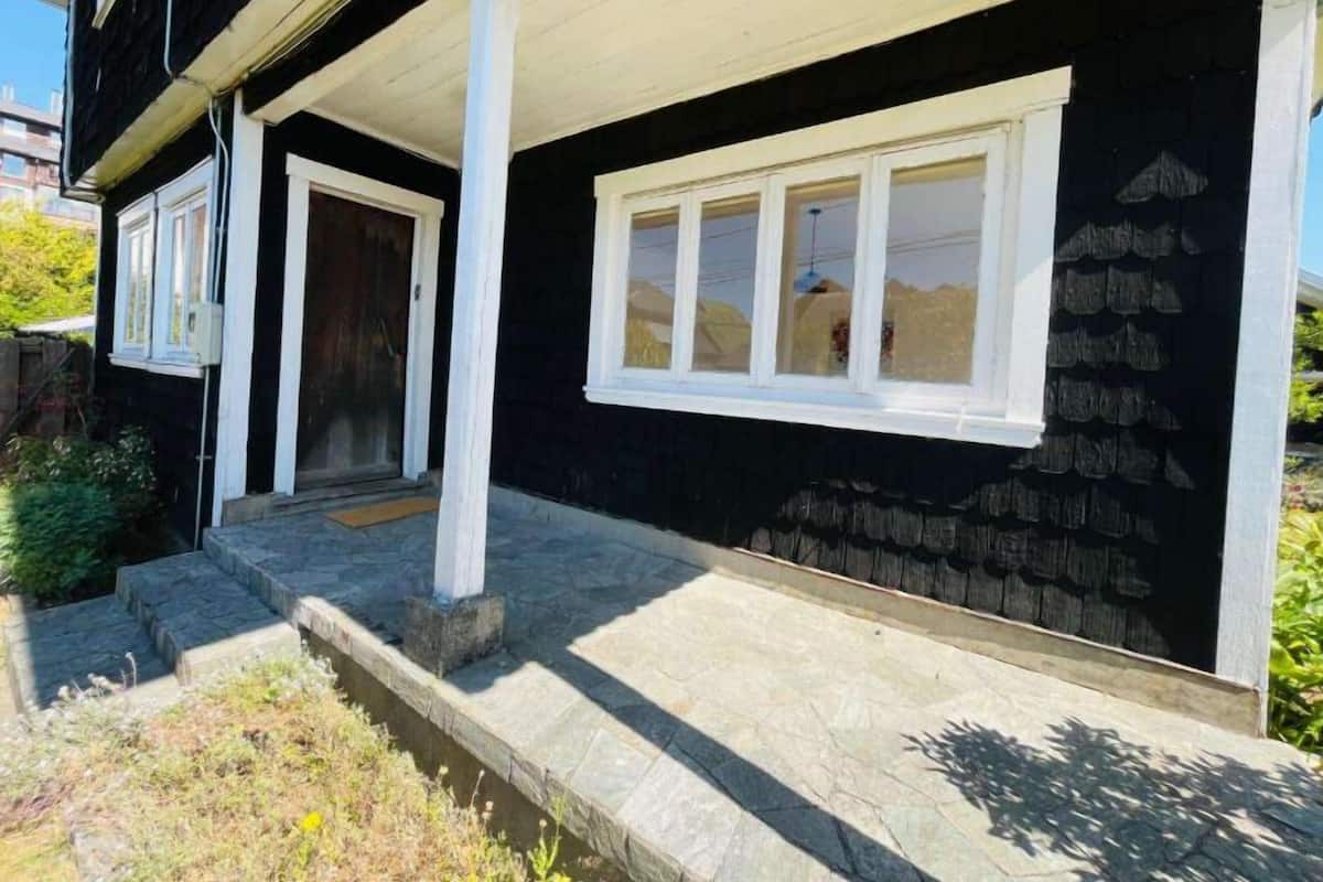 Un edificio negro con detalles blancos, una puerta principal y una ventana.