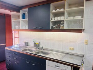 Una cocina con un lavamanos doble, armarios oscuros y paredes con azulejos blancos.