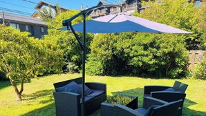 An outdoor seating area with wicker furniture and a large umbrella. - Hotel Casa Ellies Boutique (Puerto Varas)