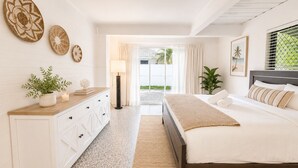 Quarto com cama, mesa de cabeceira, luminária e pratos decorativos.