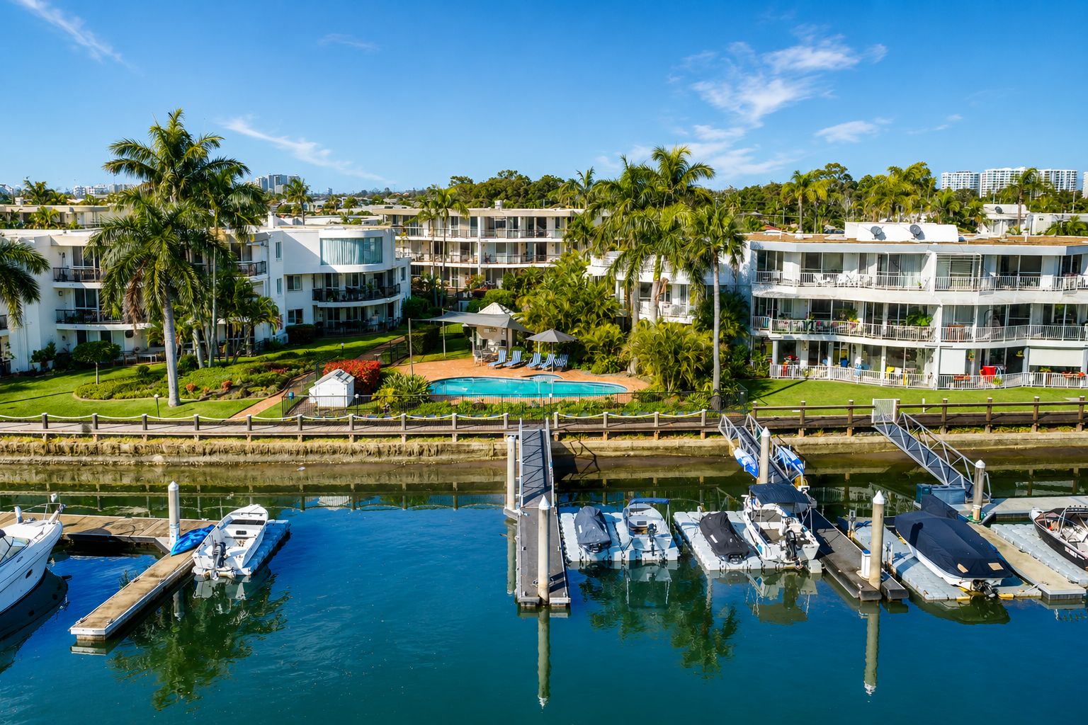 A marina with boats docked, a swimming pool, and multi-story buildings with balconies.