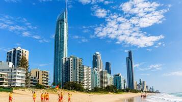 A beach with people, a sandy shore, and a city skyline with tall buildings.