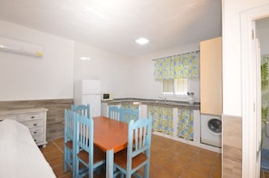A compact kitchen with a dining table, chairs, a refrigerator, a microwave, and a washing machine. - Samuel house with community pool and porch (Conil De La Frontera)