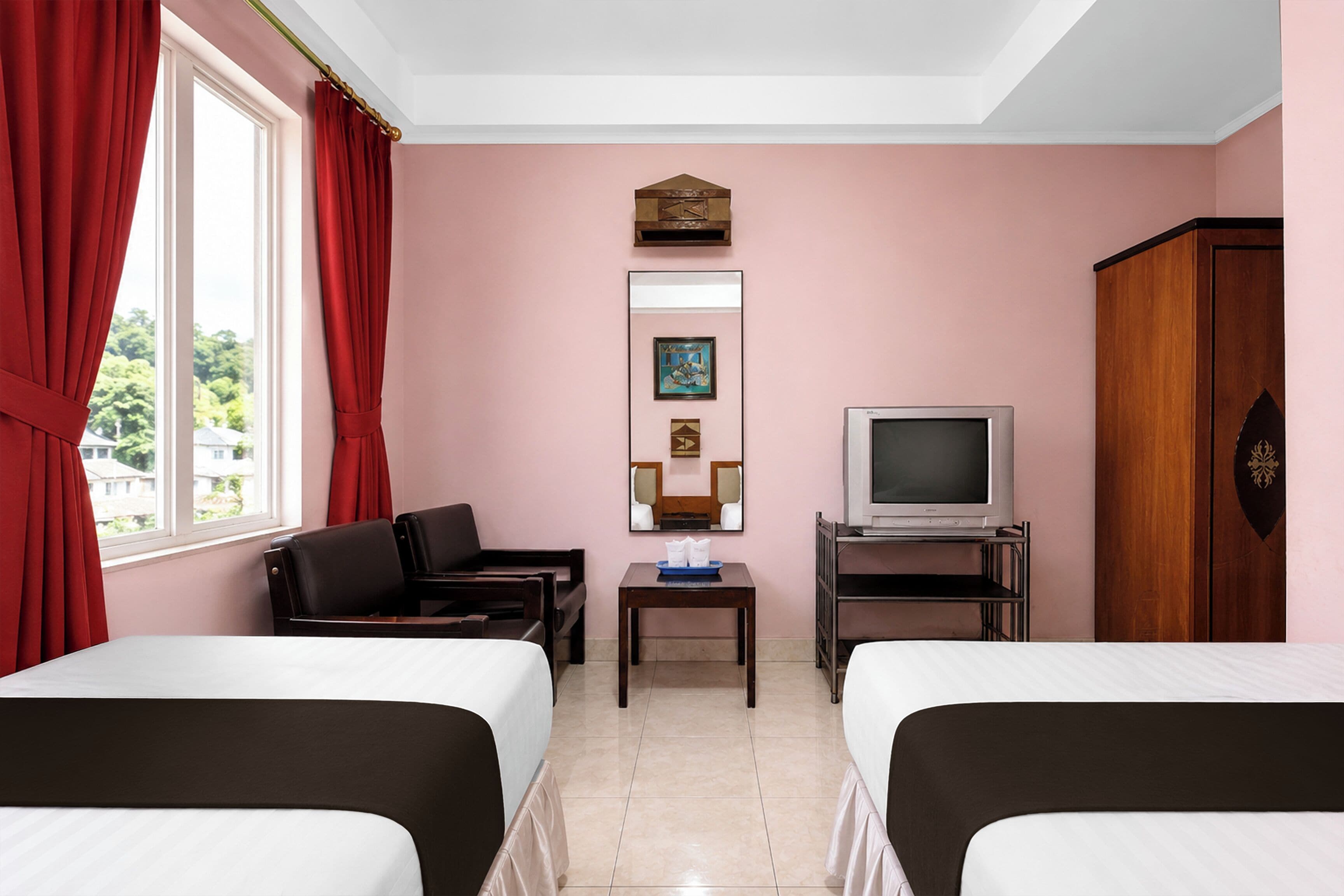 A hotel room with two beds, a TV, a small table, and a mirror on the wall.