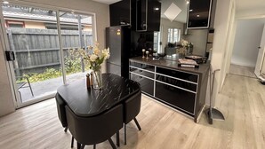A modern kitchen with a dining table, black cabinets, and a large window. - Beautiful 4 bedroom for short or long term stay! (Hastings)