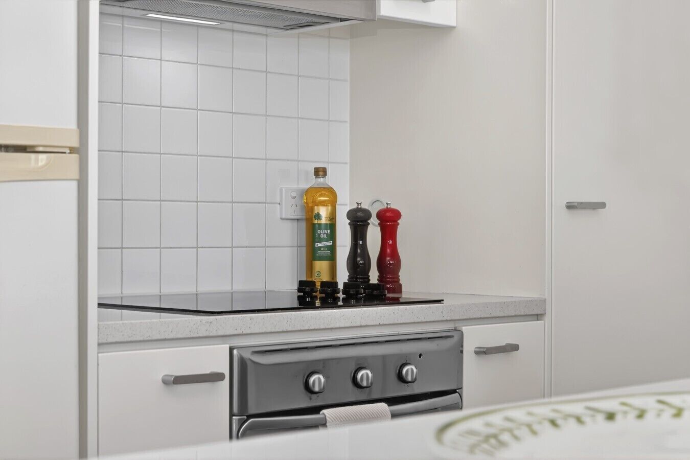 A kitchen with white cabinets, a stainless steel oven, and two pepper mills on the countertop.