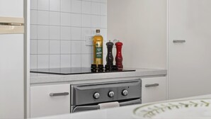 Une cuisine avec des meubles blancs, un four en acier inoxydable et deux moulins à poivre posés sur le plan de travail.