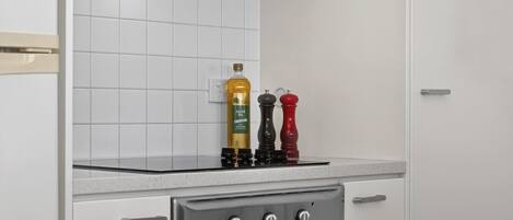 A kitchen with white cabinets, a stainless steel oven, and two pepper mills on the countertop.