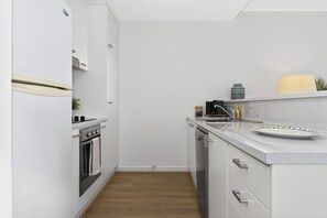 Eine kleine Küche mit weißen Schränken, einem eingebauten Ofen und einer Arbeitsplatte mit Spüle und Dekoration.