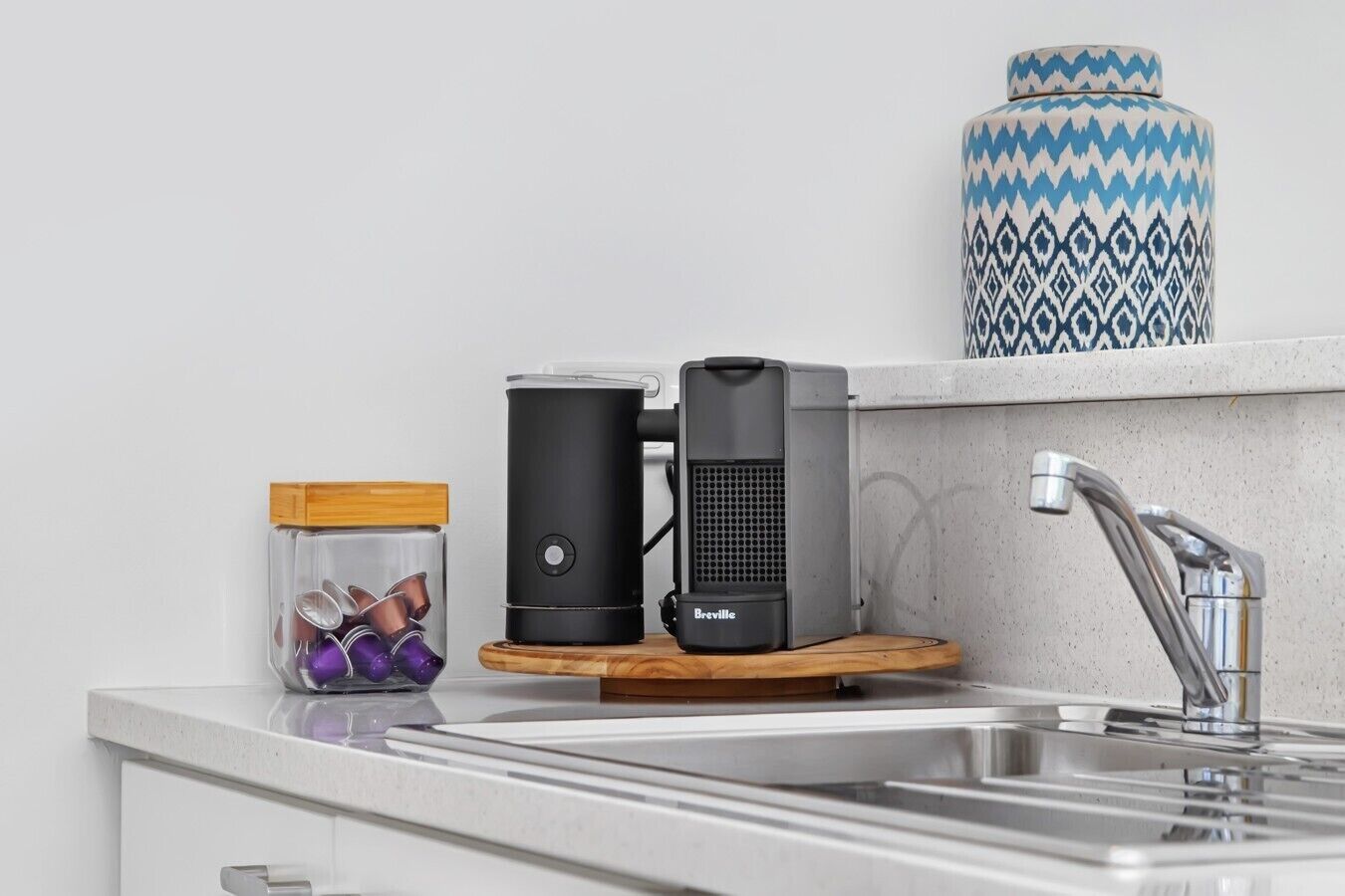 A kitchen with a coffee maker, a jar of utensils, and a decorative vase.
