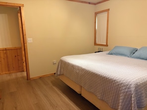 A bedroom with a bed, a wooden wardrobe, and a window with a white curtain.