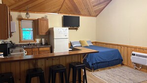 A compact kitchen with wooden cabinets, a refrigerator, a sink, and a window. - Shawnee Pines #3 - Cozy Cabin (Golconda)