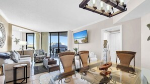 Ein modernes Wohnzimmer mit einem Glastisch, bequemen Sitzgelegenheiten und Meerblick.