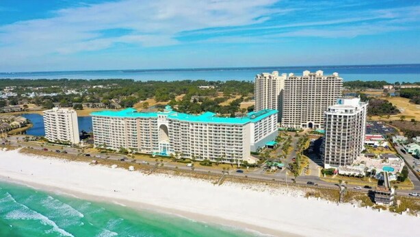 Ein Hotel direkt am Strand mit mehreren Hochhäusern, einem Strand und einem großen Wasserspiegel.
