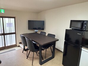 A conference room with a table, chairs, a flat-screen TV, and a Hisense microwave. - Dashing House Momoya 2 (大阪市)