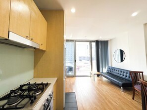 Eine moderne Küche mit Gasherd, Holzschränken und einer Glastür, die auf einen Balkon führt.