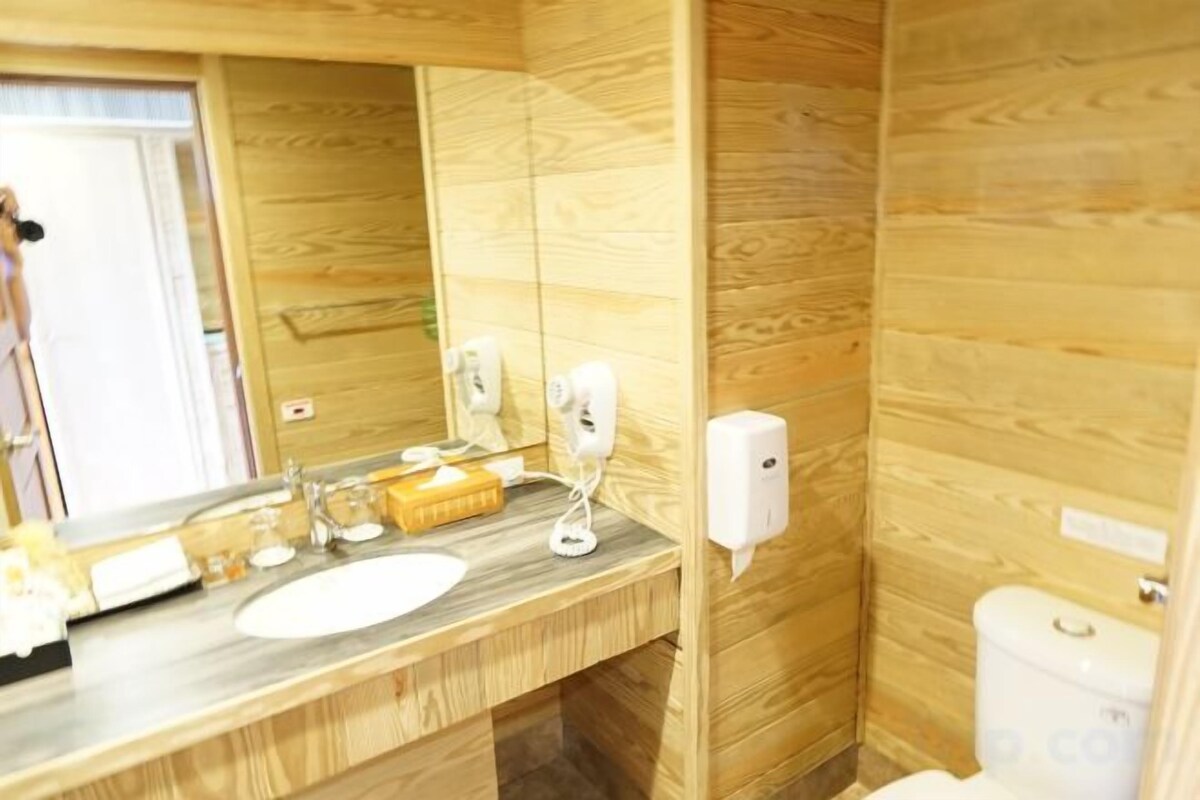 A bathroom with a wooden wall, a sink, a mirror, and a toilet.