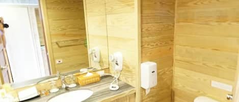 Une salle de bain avec un mur en bois, un lavabo, un miroir, des toilettes et un porte-serviettes.